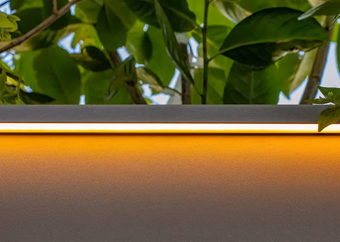 Sistema di illuminazione a LED integrato Modularte per fioriere da esterno: particolare della diffusione luminosa calda e del design del bordo tecnico.