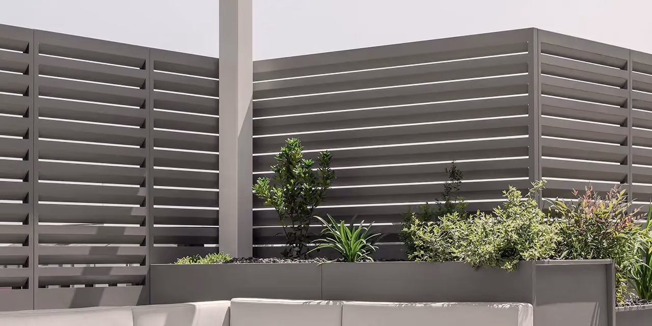 Panneaux brise-vue gris à lattes horizontales protégeant une terrasse avec bacs