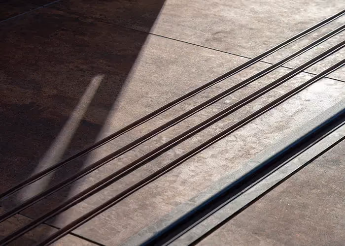 Close-up of metal tracks set into dark stone-effect flooring for a sliding opening system.