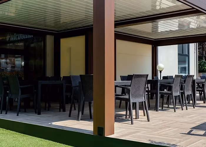 Covered terrace with modular pale wood-effect flooring, furnished with outdoor tables and chairs.