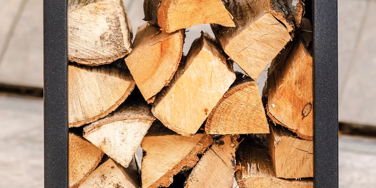 Close-up of a dark metal log store filled with cut logs