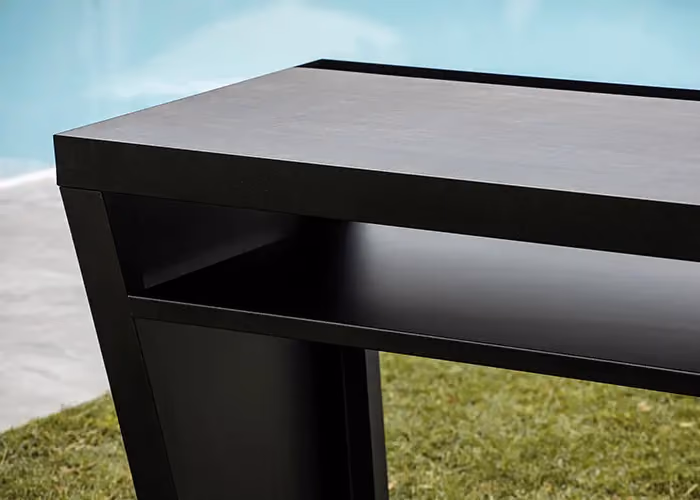 Close-up of the side surface of a modern outdoor barbecue in black metal, set beside a swimming pool.
