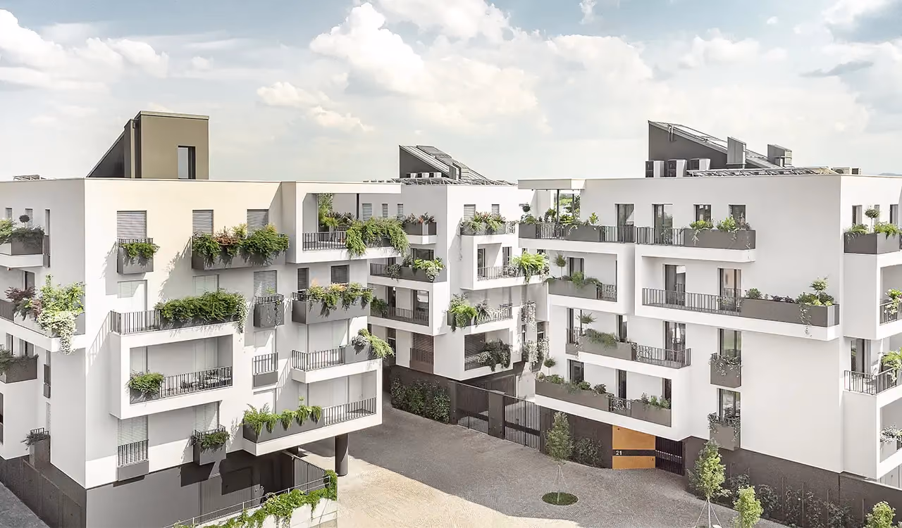 Exterior view of a complex of modern white residential blocks, with many staggered balconies dressed with large grey planters full of green plants.